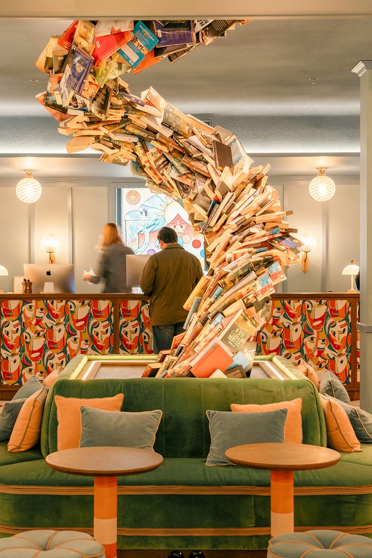 The reception of a hotel in Copenhagen, Denmark, that has books stacked to create the shape of a tree in the center of the reception area Hotel Reception Design, Hotel Ceiling, Copenhagen Hotel, Hotel Reception, Colored Ceiling, Suspended Ceiling, Reception Design, Ceiling Tiles, Copenhagen Denmark