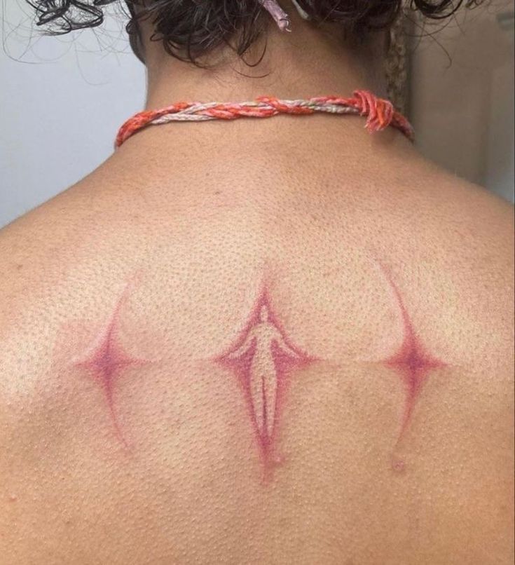 the back of a woman's shoulder with red ink on her upper arm and chest