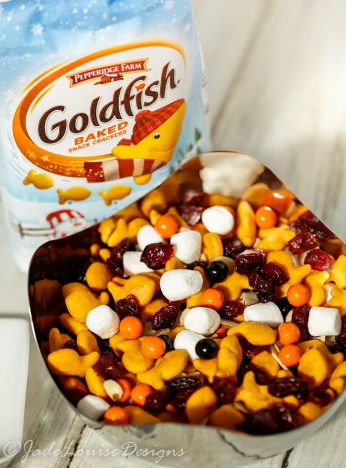 a bowl filled with candy and marshmallows next to a bag of goldfish crackers