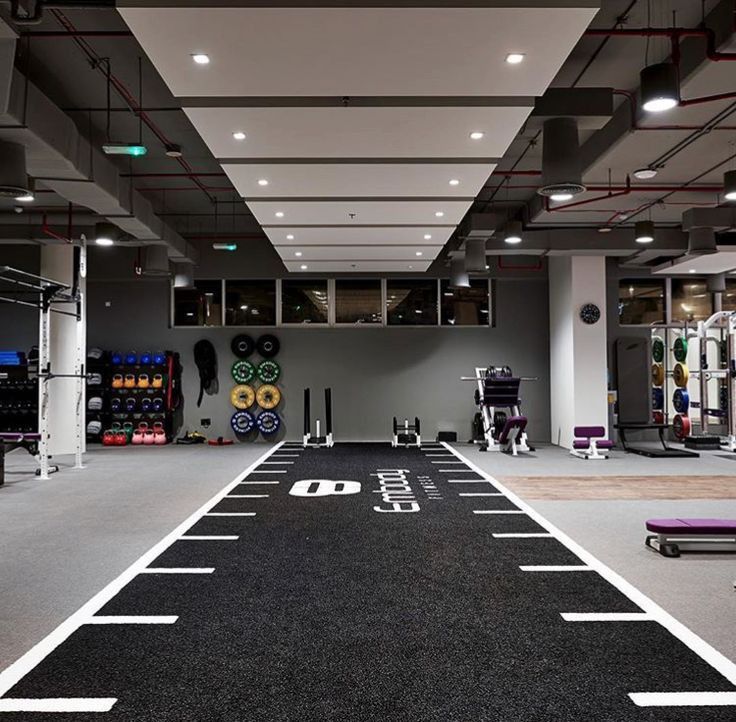 an empty gym with no people or equipment on the floor and several exercise machines in the background