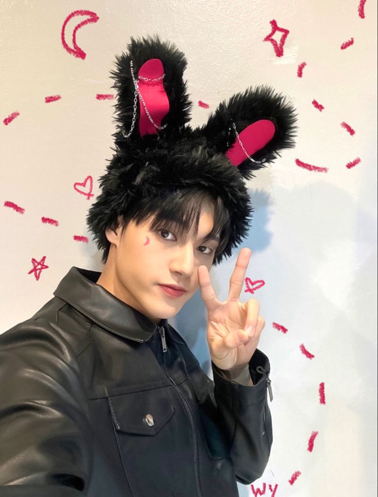 a man with black hair and bunny ears making the peace sign