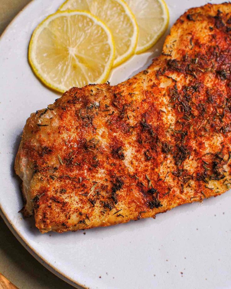 a piece of fish on a plate with lemons