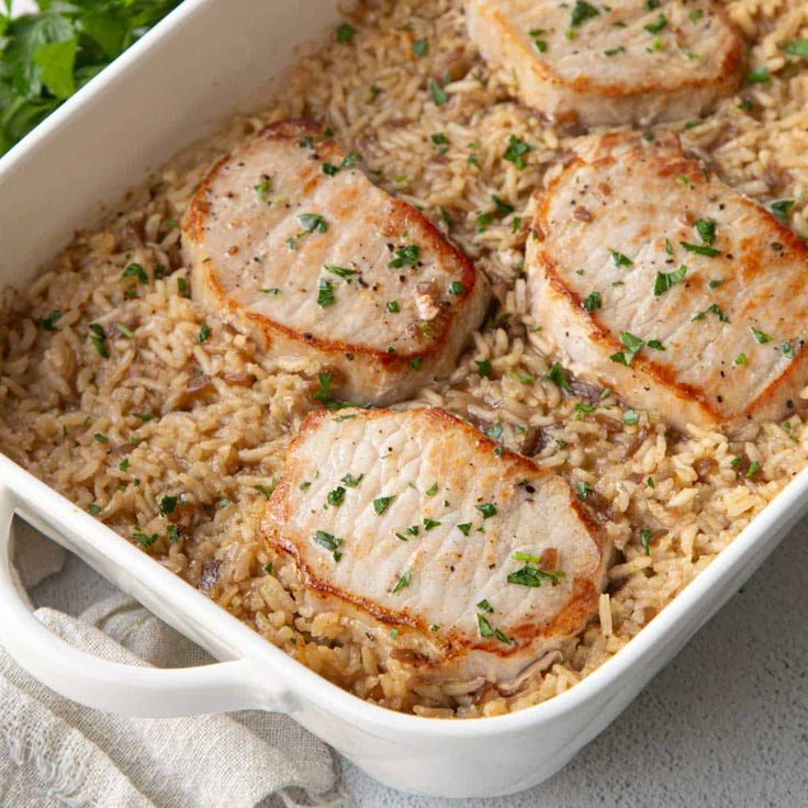 chicken and rice casserole with parsley garnish in a white dish