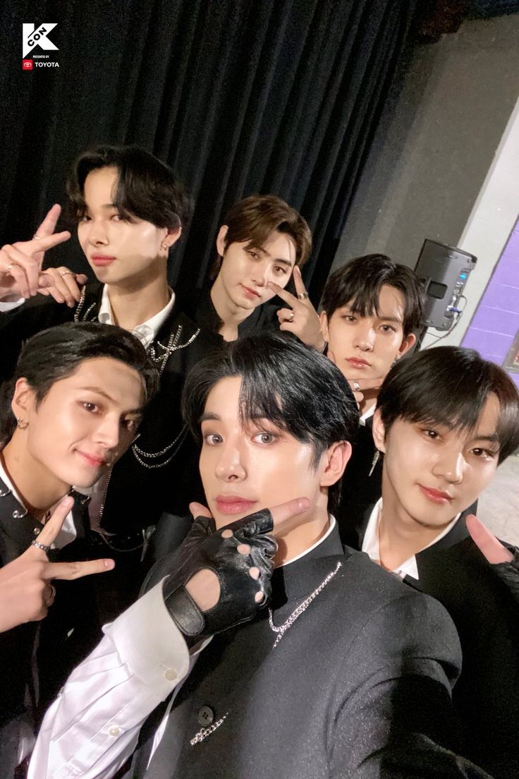 group of young men posing for photo in front of black curtain with peace sign on their fingers