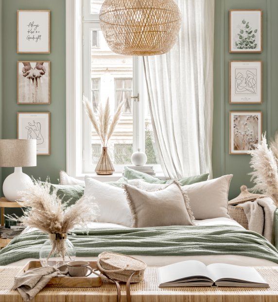 a bedroom with green walls, white curtains and pictures on the wall above the bed