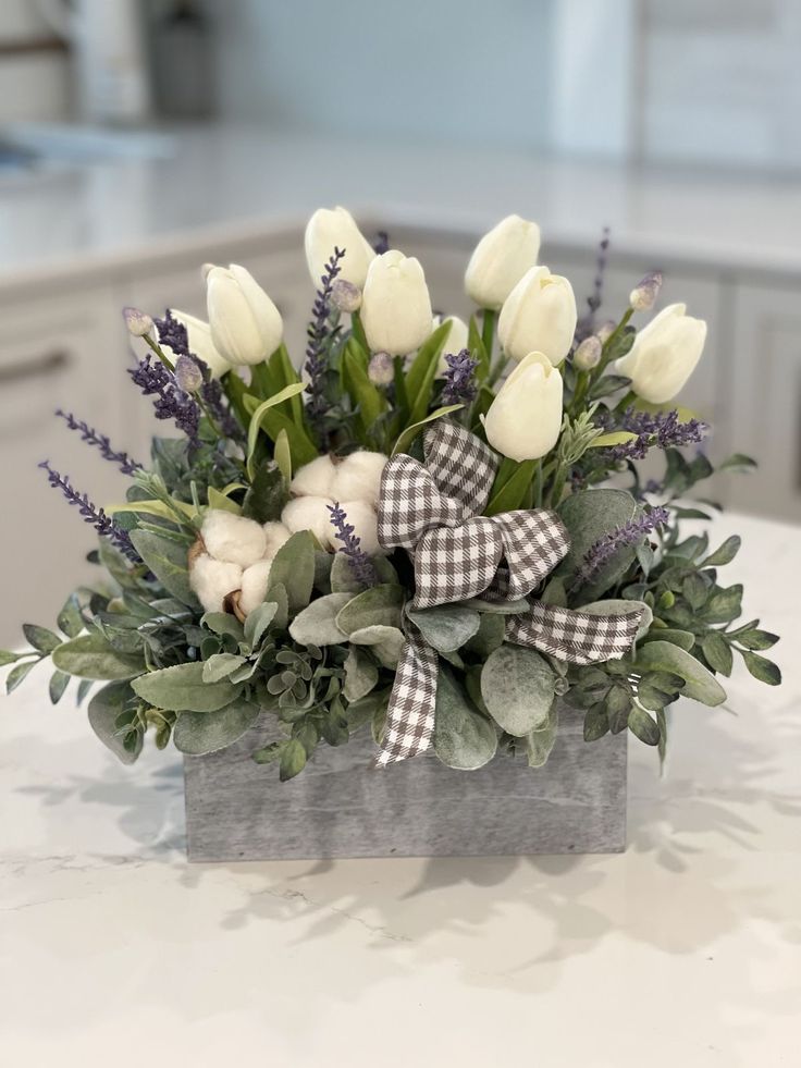 a bouquet of white tulips and greenery in a wooden box on a kitchen counter