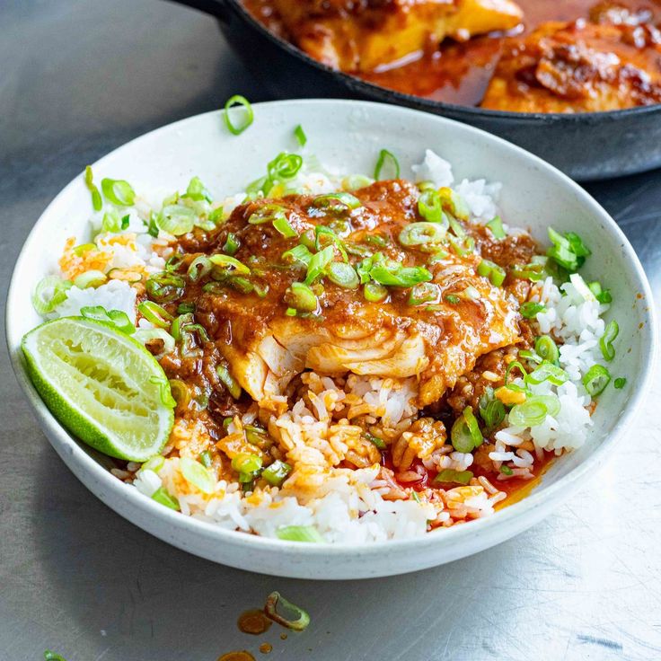 a white bowl filled with rice and meat covered in sauce