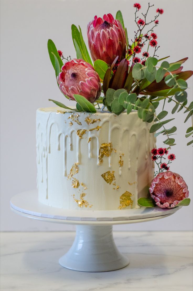 a white cake topped with flowers and greenery