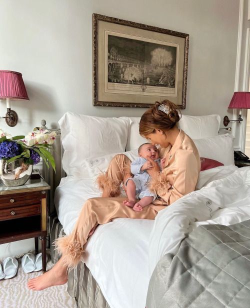 a woman sitting on top of a bed holding a baby