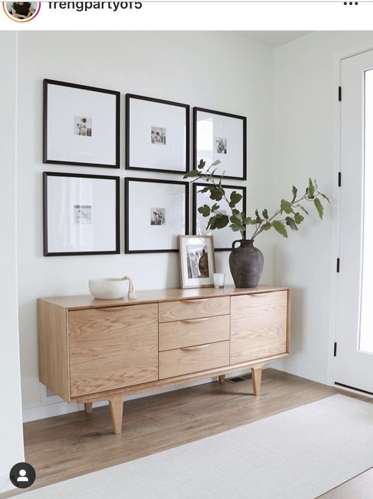 a wooden dresser sitting in front of a white wall with pictures on the wall above it