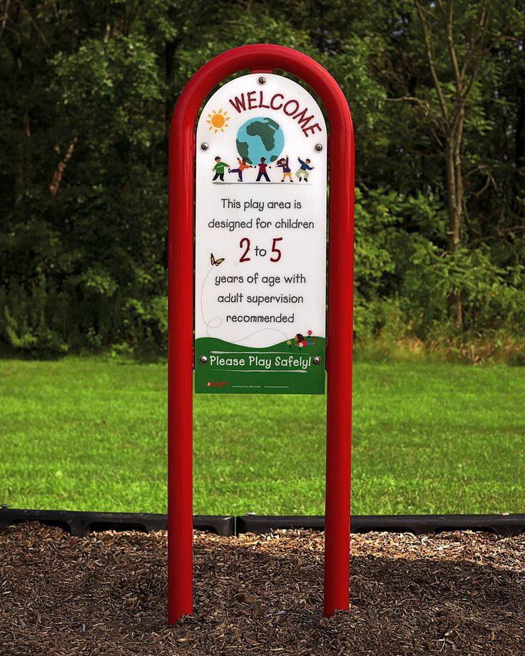 a welcome sign in the middle of a park with trees in the background and grass on the ground