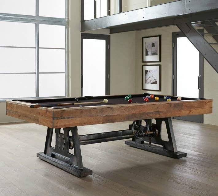 a pool table in the middle of a room with large windows and wooden flooring