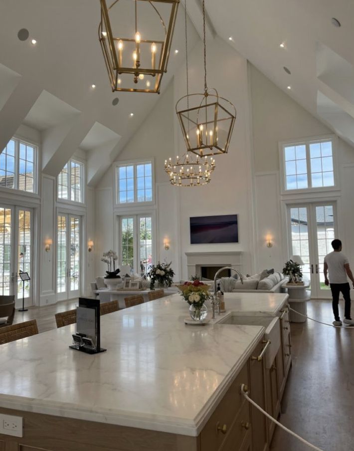 a large open concept living room with high ceilings and chandeliers hanging from the ceiling