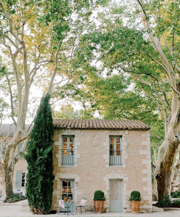 an old stone house surrounded by trees and greenery