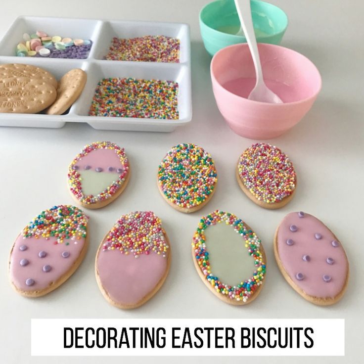 there are many decorated cookies on the table with bowls and spoons next to them