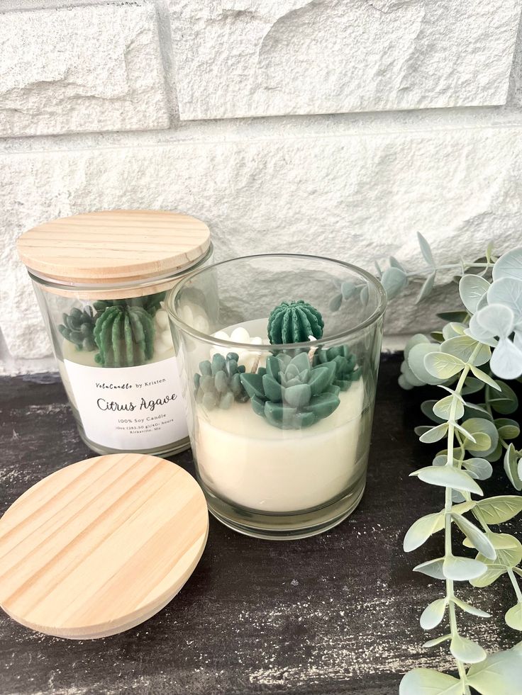 a candle sitting on top of a table next to a potted succulent