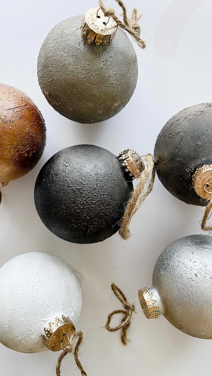 five different colored ornaments on a white surface with brown and silver decorations hanging from it's sides