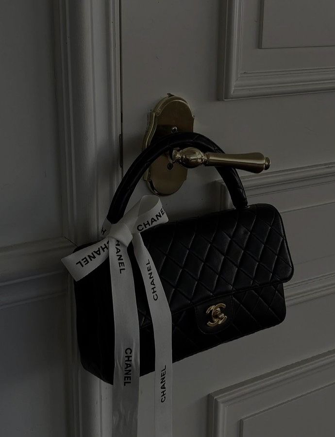 a black and white purse hanging on a door handle with a ribbon attached to it