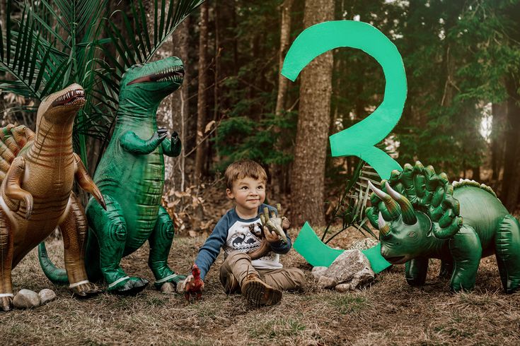 a young boy sitting in front of three dinosaur statues with the letter q on them