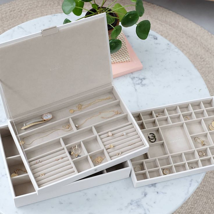 an open jewelry box sitting on top of a table next to a potted plant