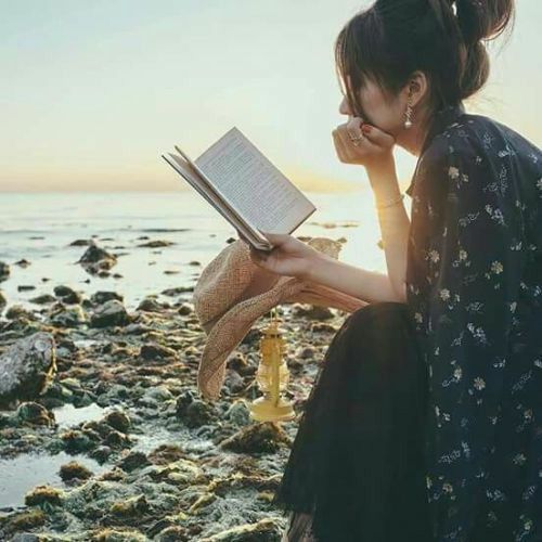 a woman reading a book on the beach