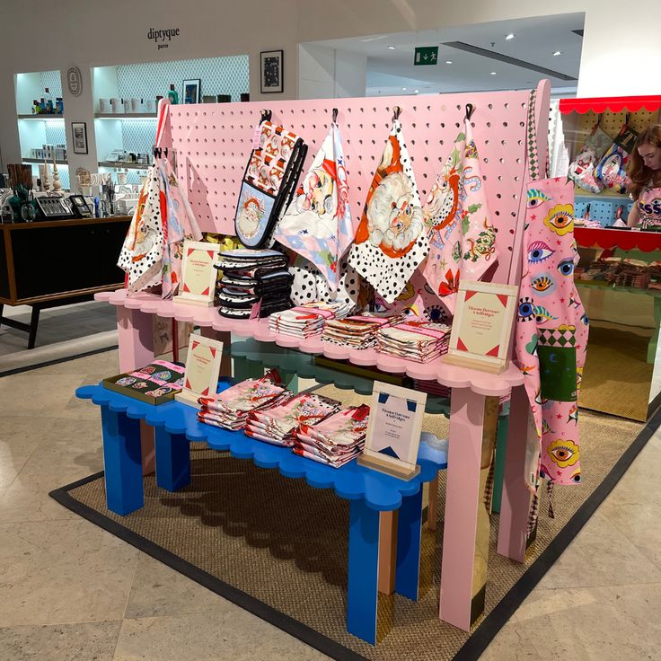 there is a pink bench with many items on it in the store and people are looking at them