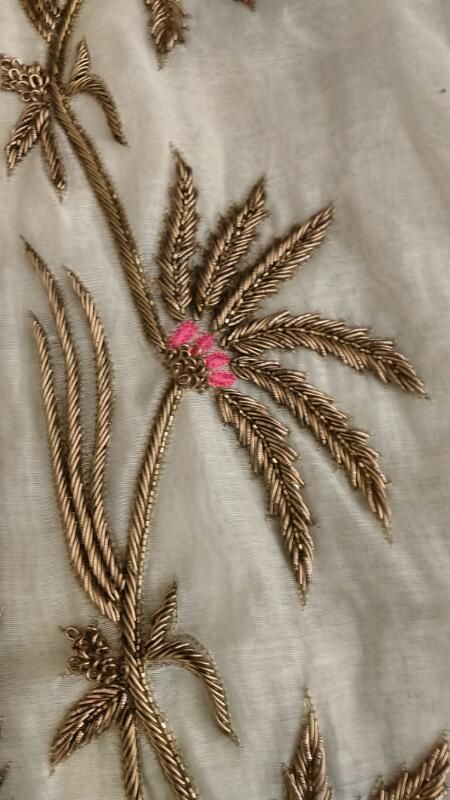 an embroidered fabric with gold and pink flowers on it