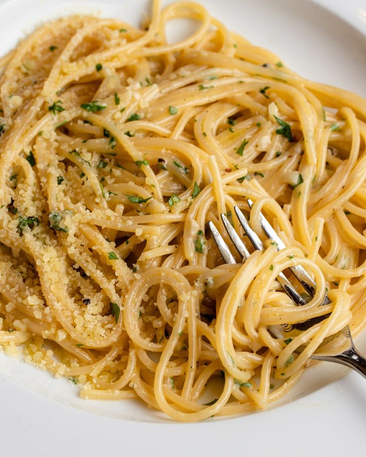 a white plate topped with spaghetti and parmesan cheese