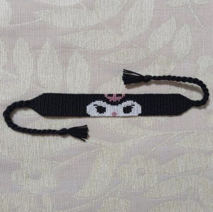 a black and white cat headband with a pink bow on the end is shown