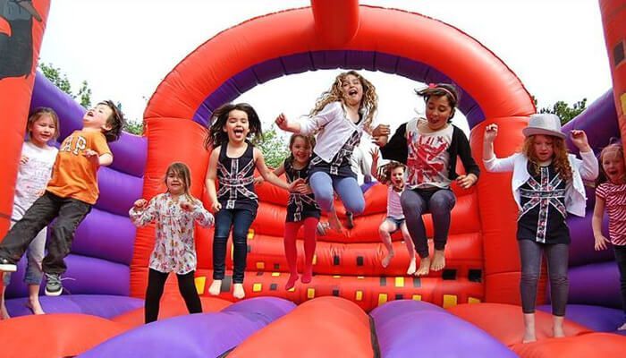 a group of children jumping on an inflatable slide