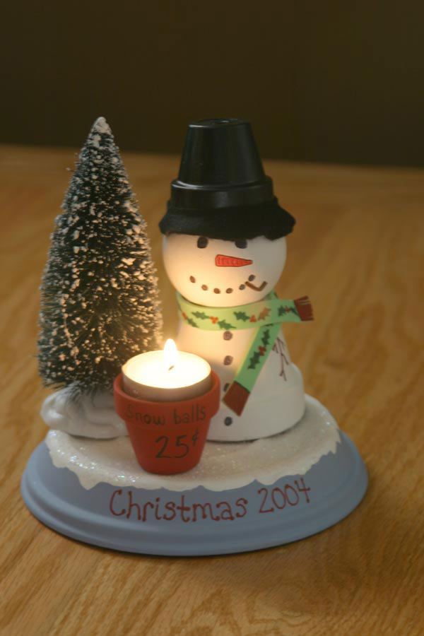 a small snowman next to a lit candle on a table