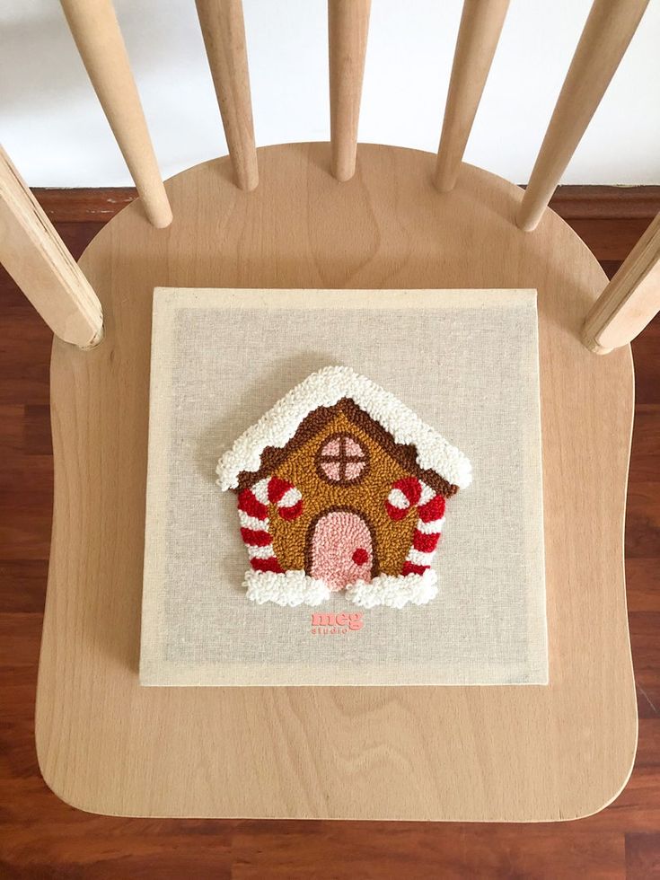 a wooden chair with a small embroidered house on it