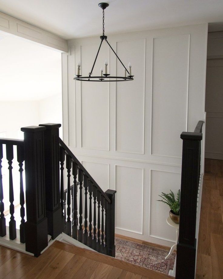 an empty living room with white walls and wood flooring is seen from the stairs