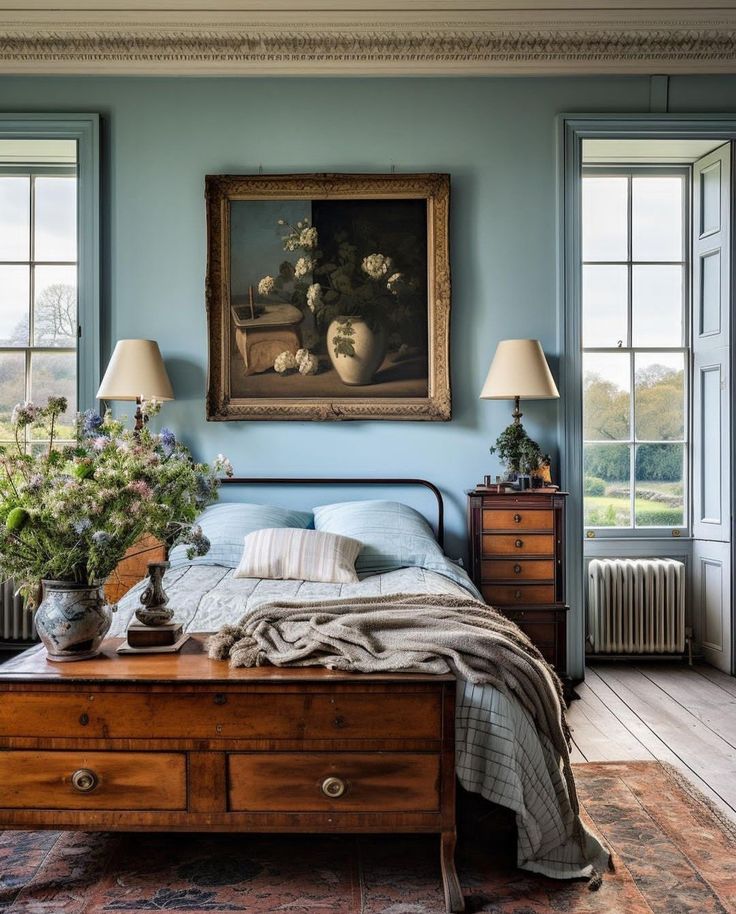 a bedroom with blue walls and wooden floors has a painting on the wall above the bed