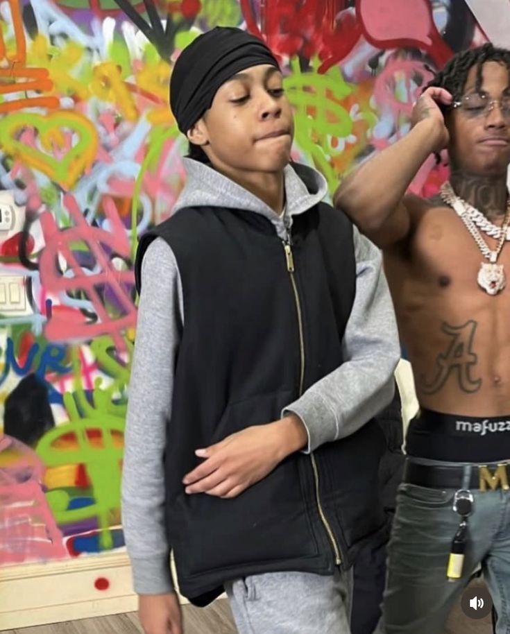 two young men standing next to each other in front of graffiti