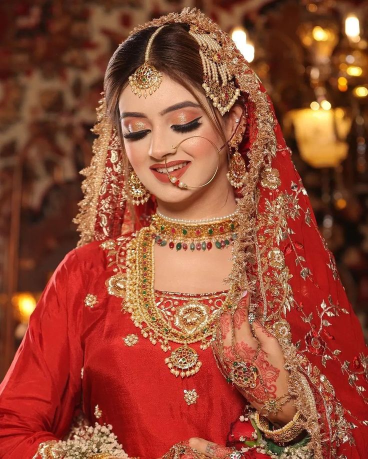 a woman in red and gold makeup looks like she's getting ready for her wedding