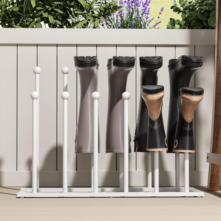 four black and white rain boots lined up against a fence with purple flowers in the background