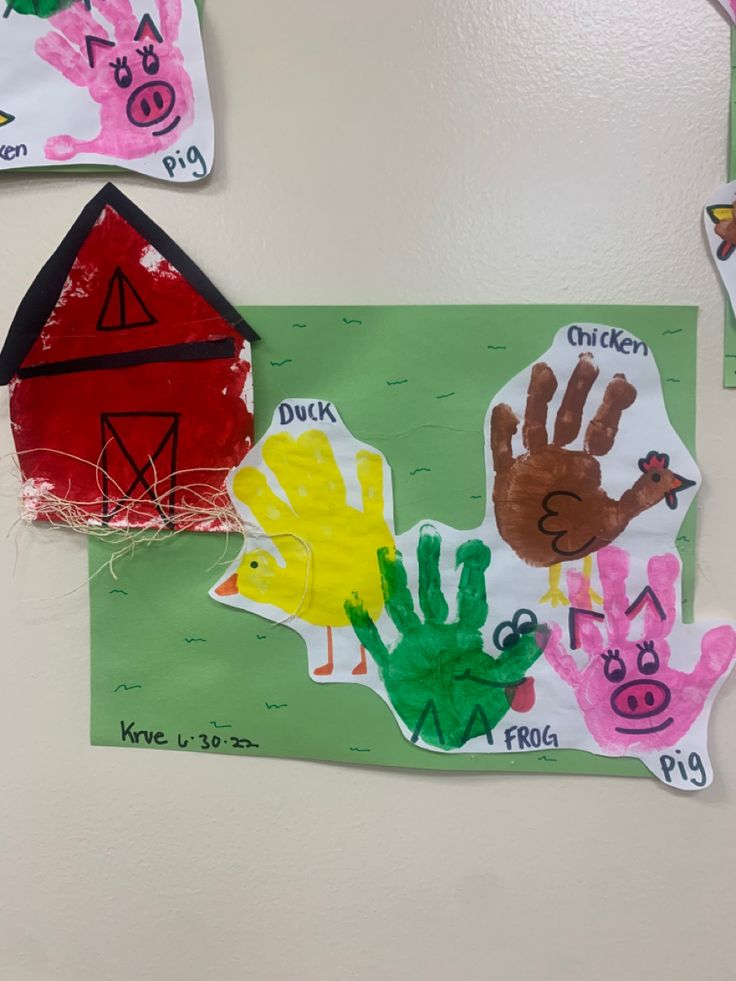 some handprints are hanging on the wall next to a paper house and farm animals