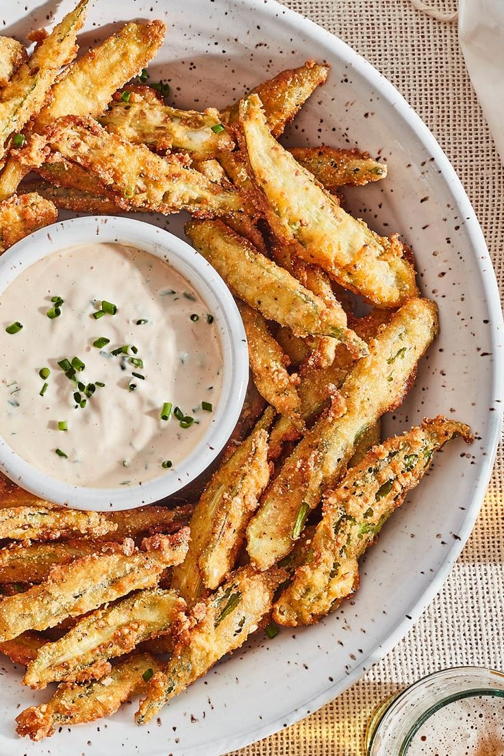 a white plate topped with french fries covered in ranch dip and garnished with parsley