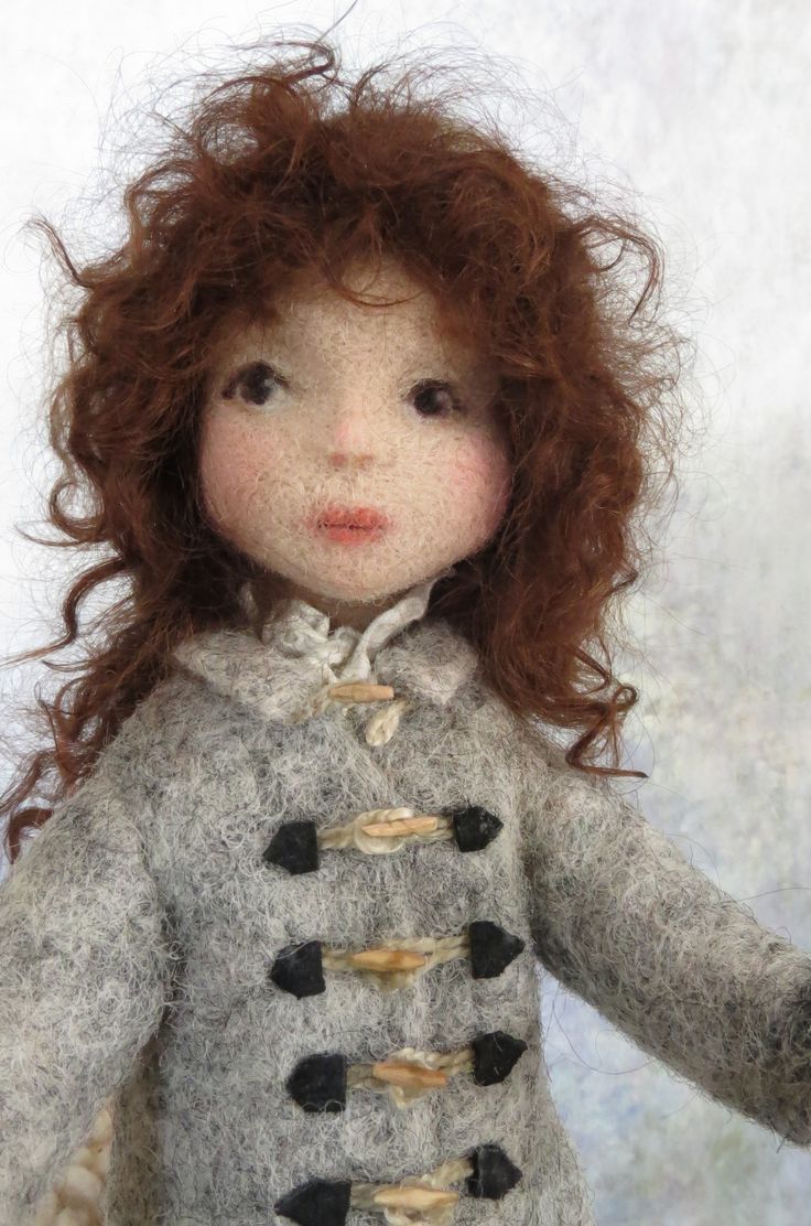 a close up of a doll with red hair wearing a gray coat and black pants