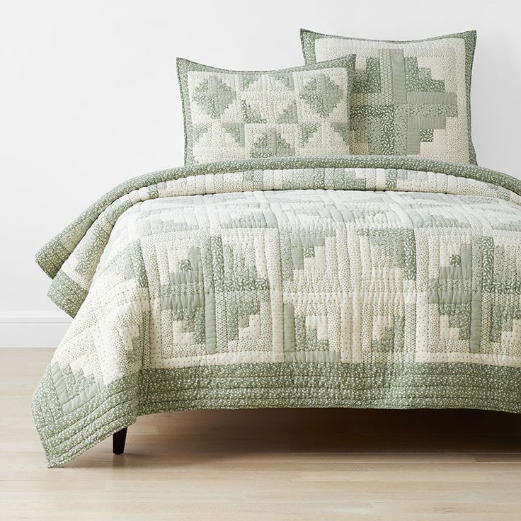 a green and white quilted bed with pillows