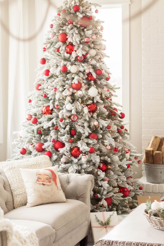 a white christmas tree with red and silver ornaments in a living room decorated for the holidays