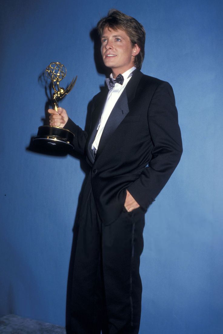 a man in a tuxedo holding an award for outstanding television series, the office