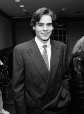 a man in a suit and tie standing next to two women