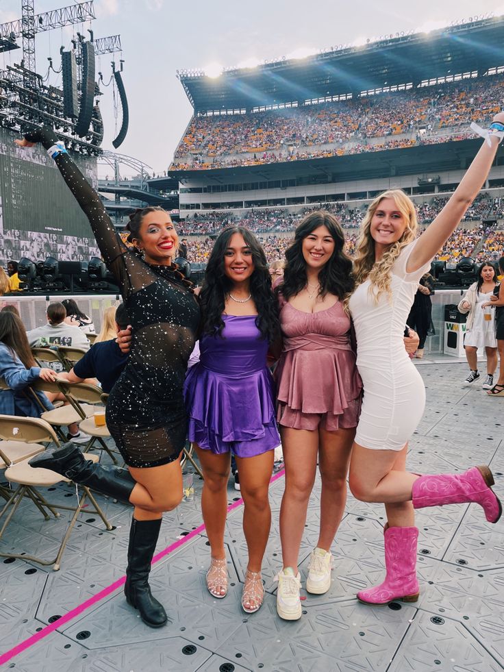 three beautiful women standing next to each other in front of a crowd at a football game