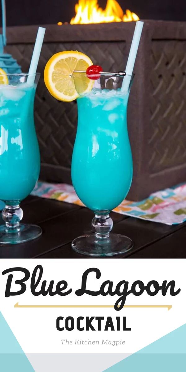 two blue lagoon cocktails sitting on top of a table next to a fire place