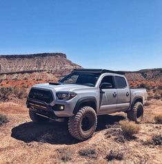 a silver truck parked in the desert with mountains in the background