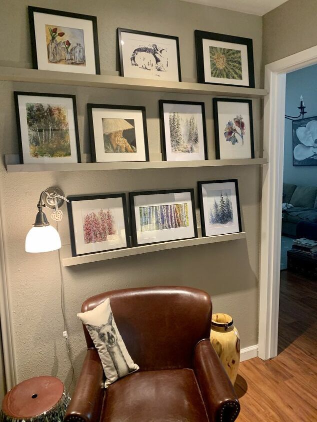 a brown leather chair sitting in front of a wall filled with framed pictures on it