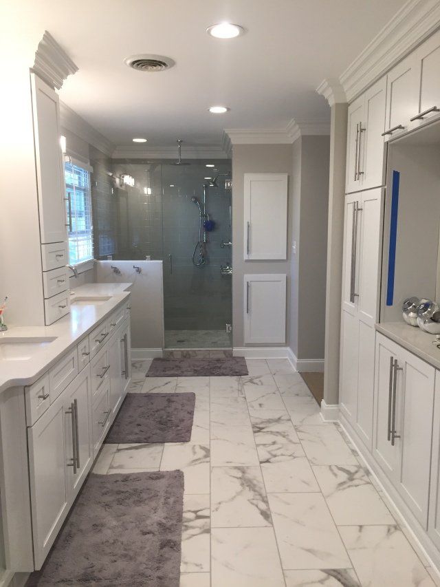 a large bathroom with marble floors and white cabinets