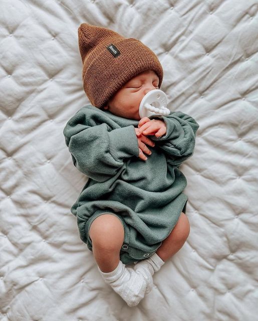 a baby is laying on a bed with a pacifier in it's mouth